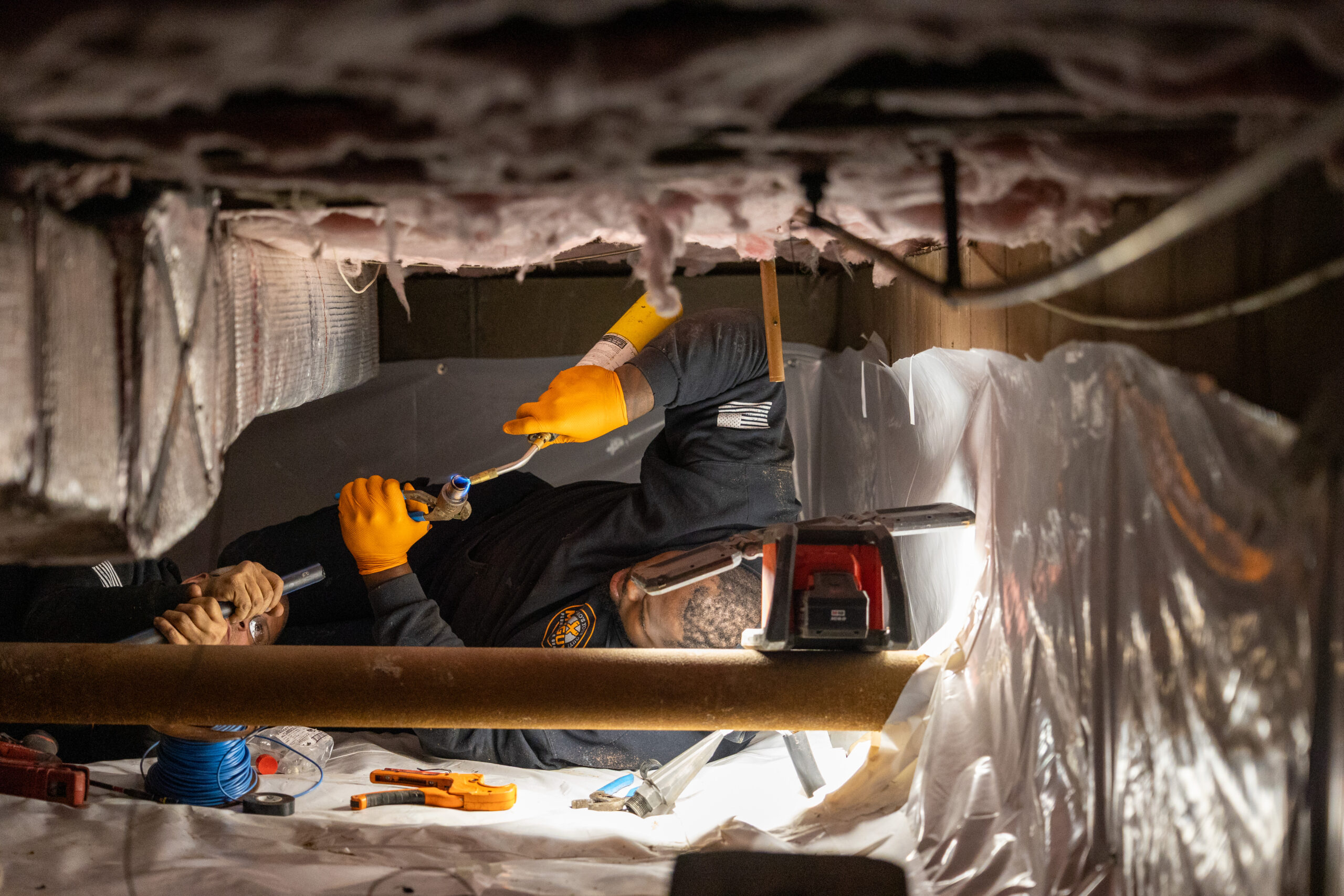 Plumber welding in crawl space